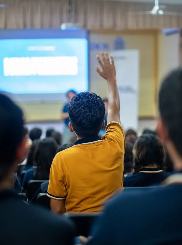 A student raises his hand during a seminar in an educational setting.