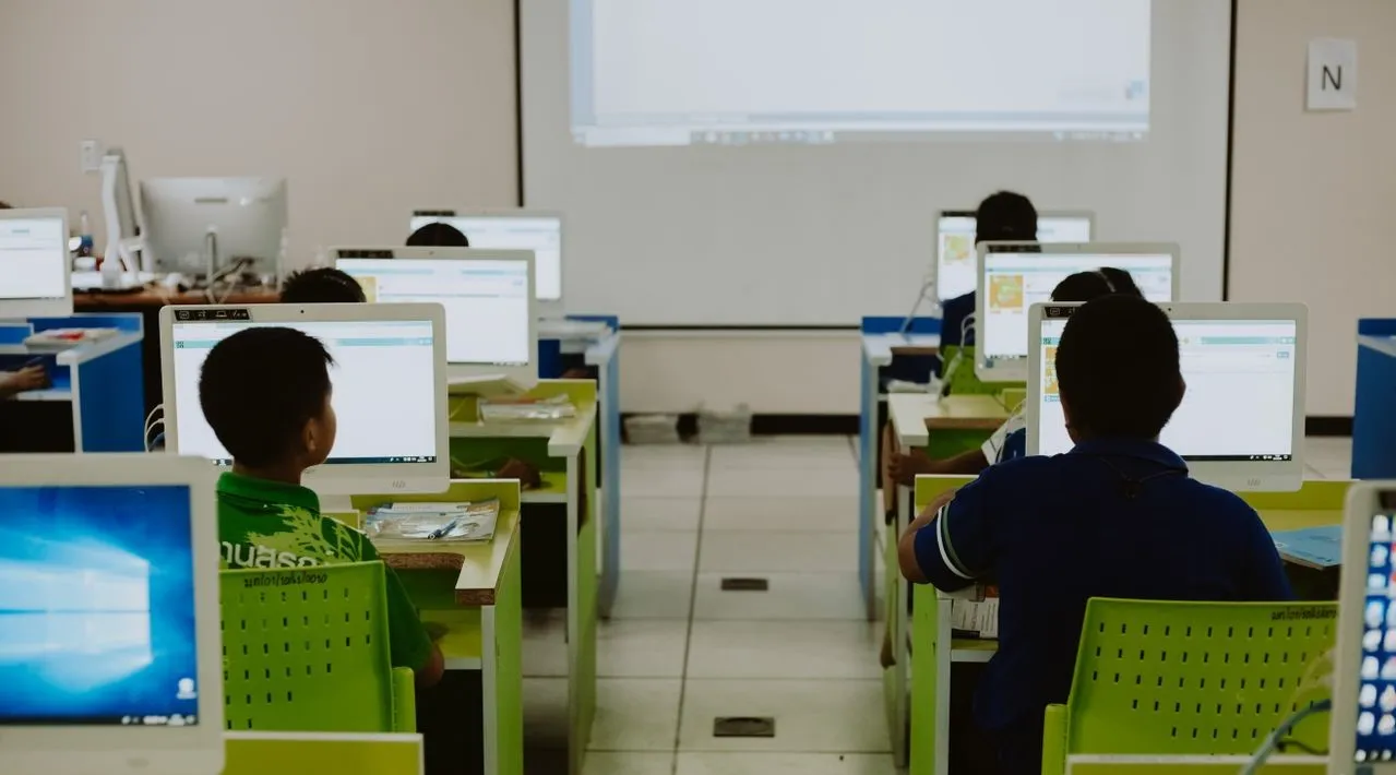 Children focus on computers in a modern classroom setting.